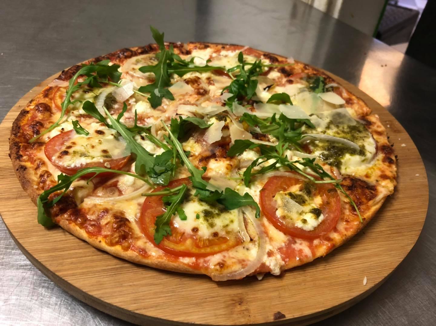 Pizza mit Rucola, Tomaten, Zwiebeln und Parmesan