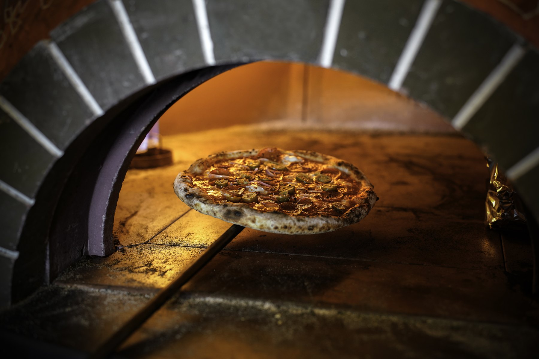 Frisch gebackene Pizza auf dem Schieber im Steinofen